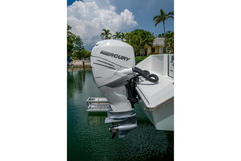  Yacht Photos Pics 2023 SeaHunter 31 Tournament boat with Mercury Verado outboard engine, docked by tropical foliage.