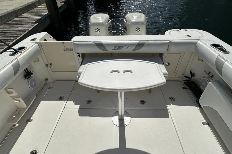  Yacht Photos Pics 2006 Boston Whaler 285 Conquest boat interior with seating and table, docked by water.