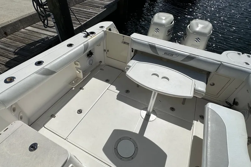  Yacht Photos Pics 2006 Boston Whaler 285 Conquest boat interior with seating and table, docked by water.