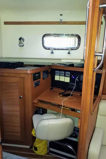 Open Agenda Yacht Photos Pics Navigation station inside 2006 Island Packet 370 sailboat, featuring wooden cabinetry and seating.