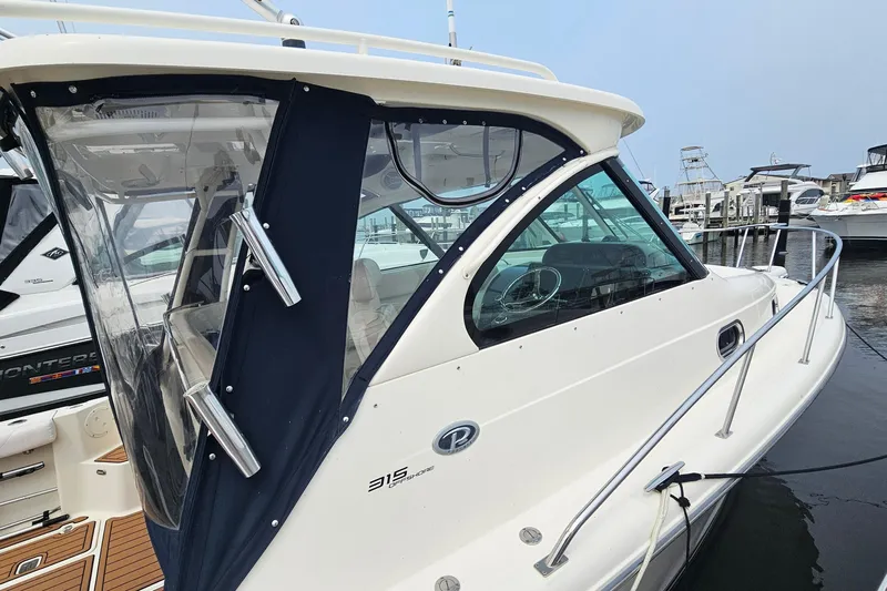  Yacht Photos Pics 2009 Pursuit OS 315 Offshore boat docked at marina, featuring sleek design and enclosed cabin.