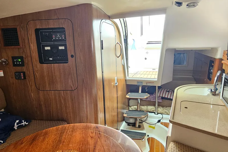  Yacht Photos Pics 2009 Pursuit OS 315 Offshore cabin interior with wood paneling and compact kitchen area.