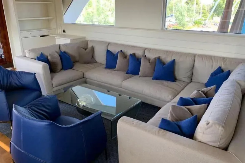  Yacht Photos Pics Luxurious yacht interior with beige sectional sofa, blue cushions, and glass coffee table, Benetti Sail Division 105.