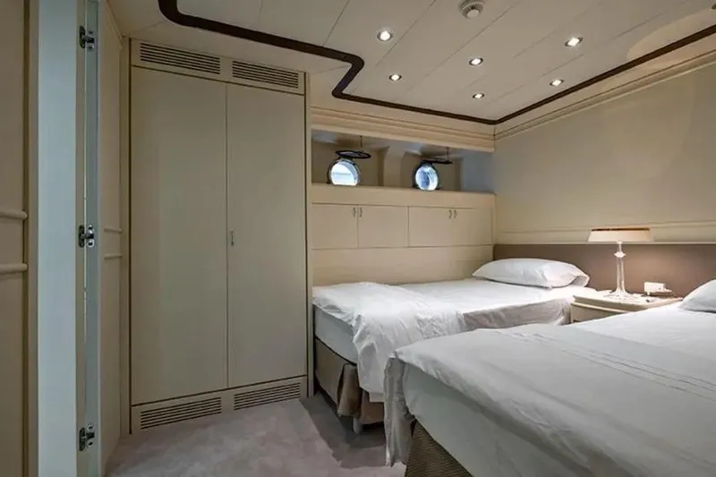  Yacht Photos Pics Luxurious twin bedroom on 2002 Benetti Sail Division 105 yacht, featuring elegant decor and porthole windows.