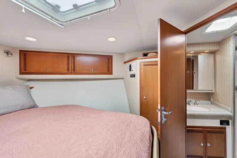  Yacht Photos Pics 2010 Cabo 45 Express cabin interior with bed, wooden cabinets, and bathroom.
