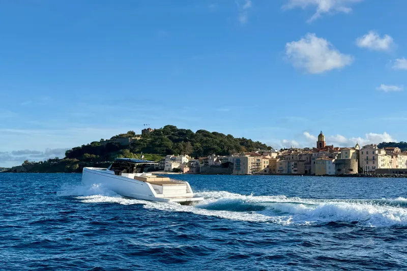 Five 3 Yacht Photos Pics 2024 Pardo Yachts 50 cruising near a scenic coastal town under a clear blue sky.