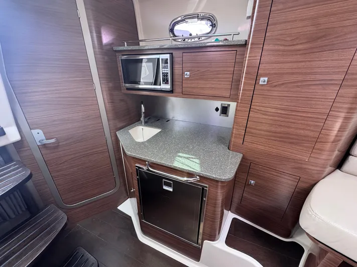  Yacht Photos Pics 2015 Boston Whaler 345 Conquest galley with microwave, sink, and wood cabinetry.