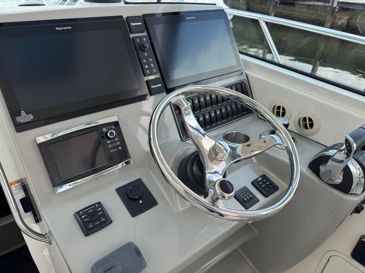  Yacht Photos Pics Control panel of a 2015 Boston Whaler 345 Conquest boat with steering wheel and navigation screens.
