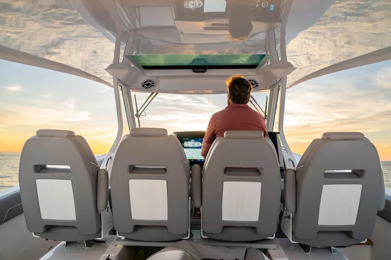 Let&rsquo;s Go Yacht Photos Pics 2025 Regal 38 SAV boat interior with captain at sunset, featuring modern seating and controls.
