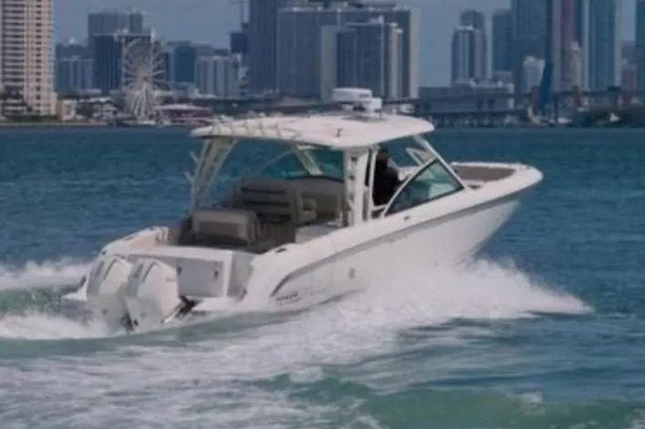  Yacht Photos Pics 2021 Boston Whaler 320 Vantage cruising on water with city skyline backdrop.