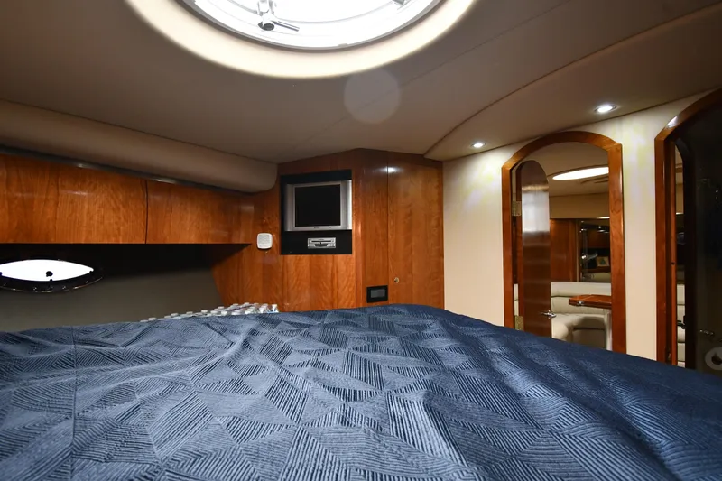This Is It Yacht Photos Pics Luxurious cabin interior of 2005 Cruisers Yachts 520 Express with wood paneling and blue bedding.