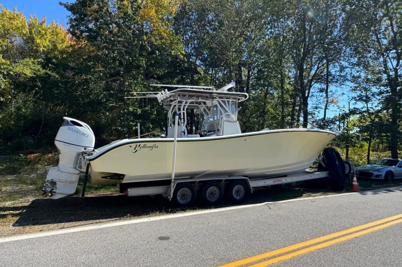  Yacht Photos Pics 2007 Yellowfin 34 Offshore boat on trailer, parked roadside with trees in background.