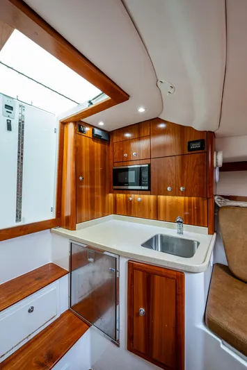 Seaclusion Yacht Photos Pics 2018 Albemarle 290 Express Fisherman cabin with wood cabinetry, sink, and microwave.