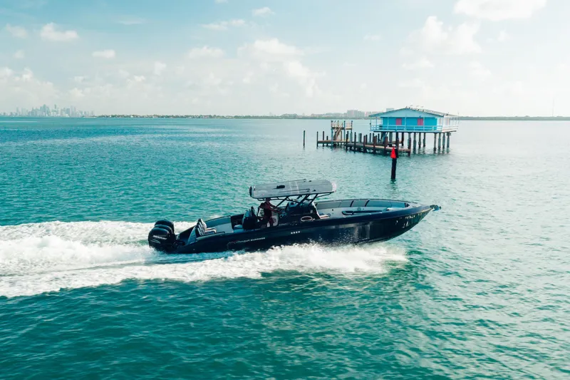 Opal Yacht Photos Pics 2014 Midnight Express 37’ Open boat cruising near a stilt house on a sunny day.