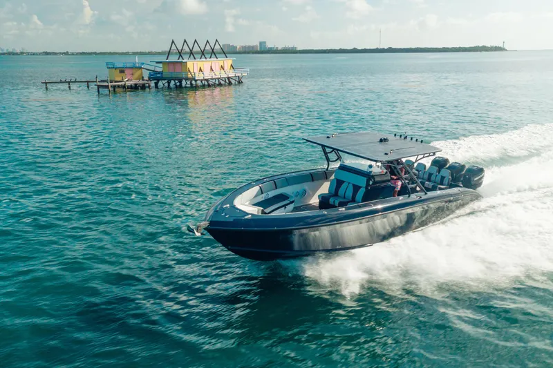 Opal Yacht Photos Pics 2014 Midnight Express 37’ Open boat cruising on clear blue water near colorful floating house.