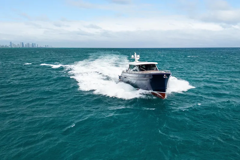 Tribu Yacht Photos Pics 2021 Steeler 60 S Performance yacht cruising on open sea with city skyline in background.