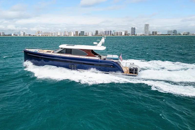 Tribu Yacht Photos Pics Steeler 60 S Performance yacht cruising on ocean with city skyline in background, 2021 model.