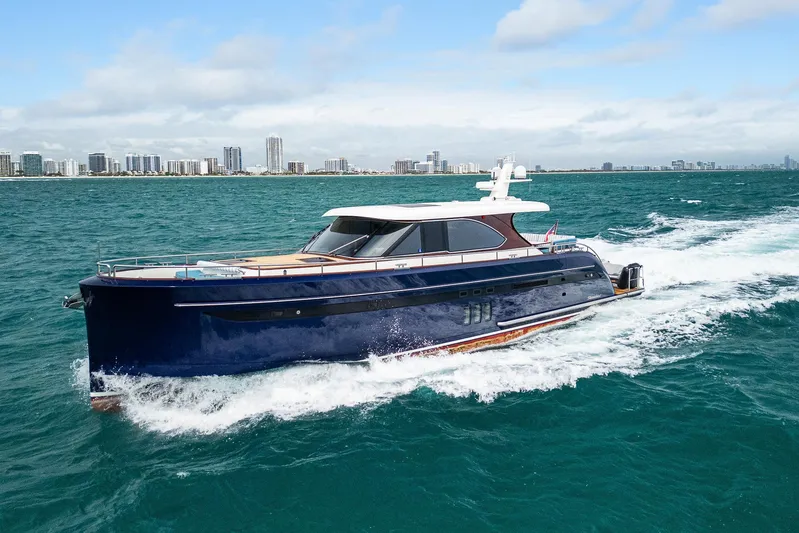 Tribu Yacht Photos Pics 2021 Steeler 60 S Performance yacht cruising on open water near a city skyline.