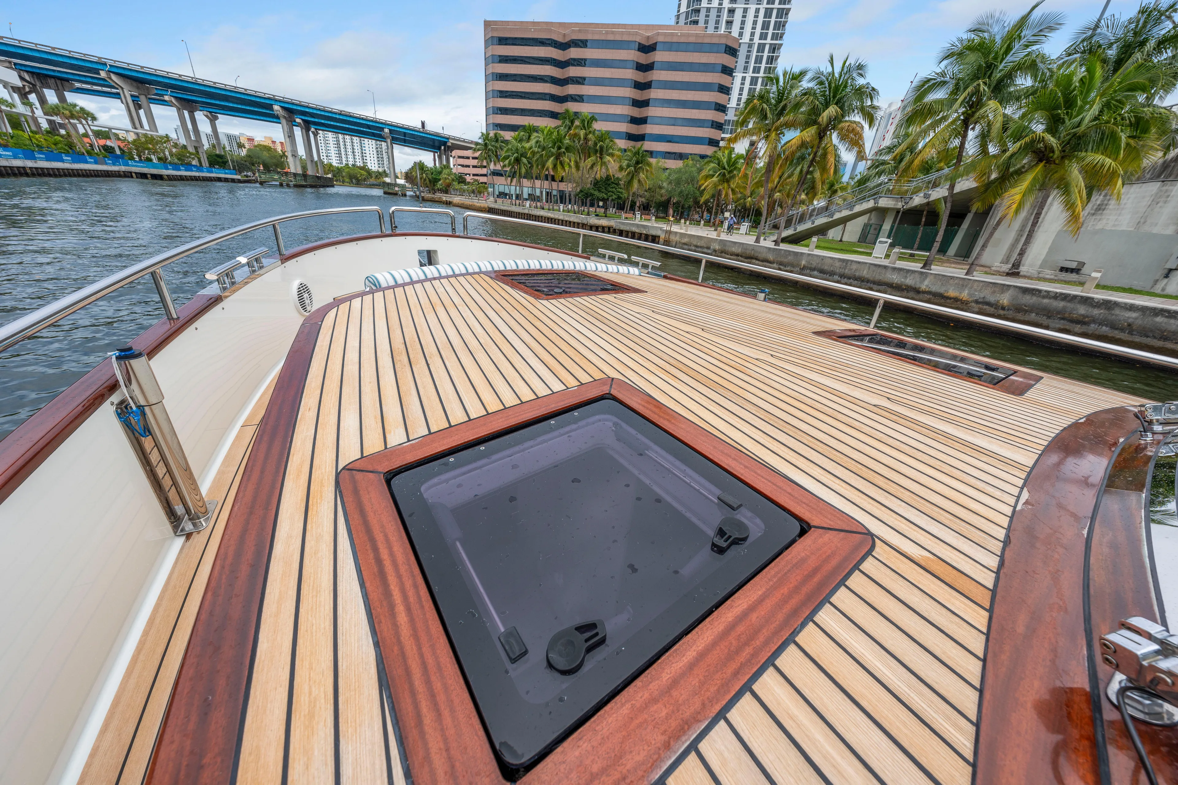 Tribu Yacht Photos Pics Steeler 60 S Performance 2021 yacht deck with sleek wood finish, docked by palm trees.