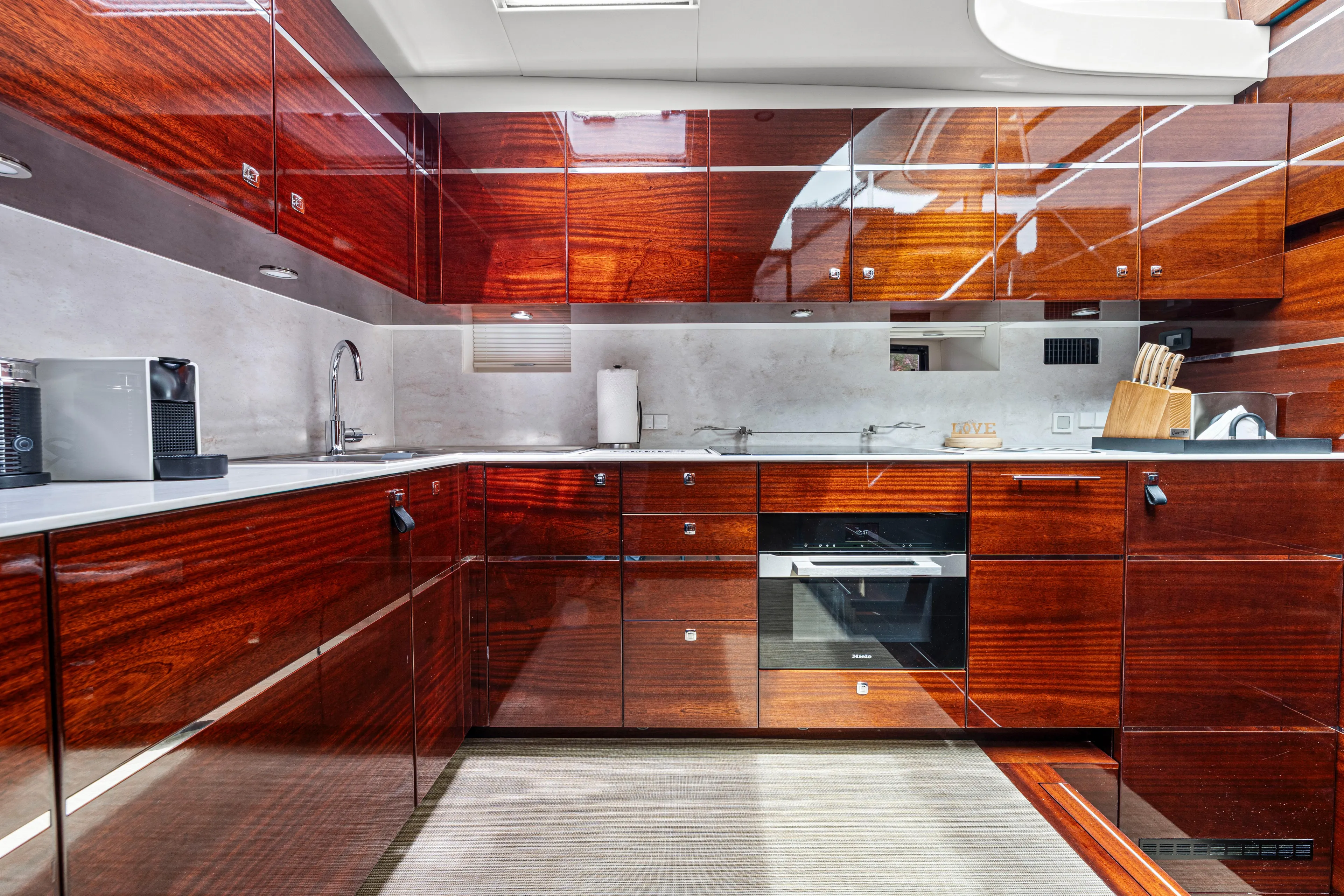 Tribu Yacht Photos Pics Luxurious yacht kitchen with glossy wood cabinets, modern appliances, and sleek design. Steeler 60 S Performance 2021.