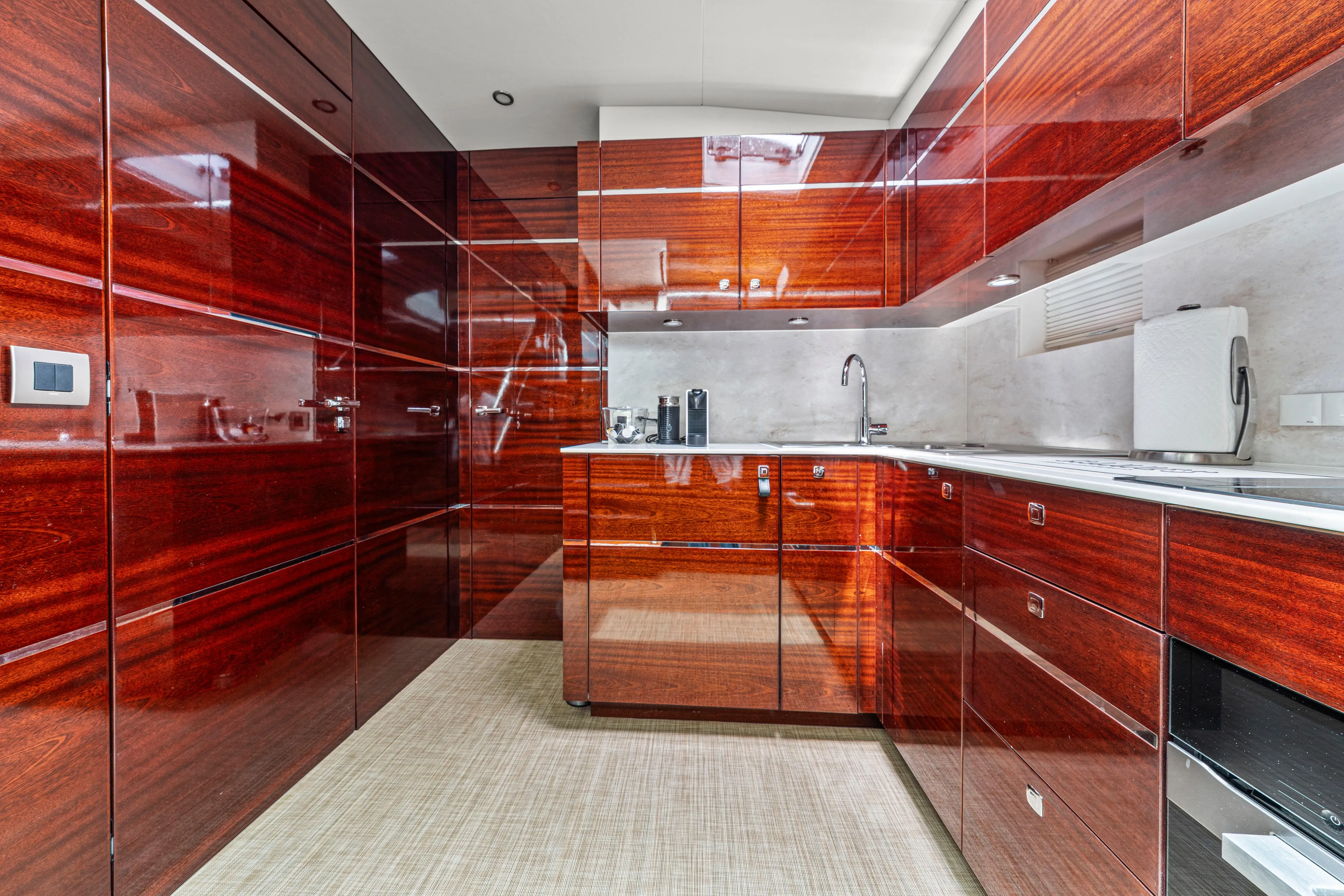 Tribu Yacht Photos Pics Luxurious yacht kitchen with glossy wooden cabinets, modern appliances, and sleek design. Steeler 60 S Performance 2021.