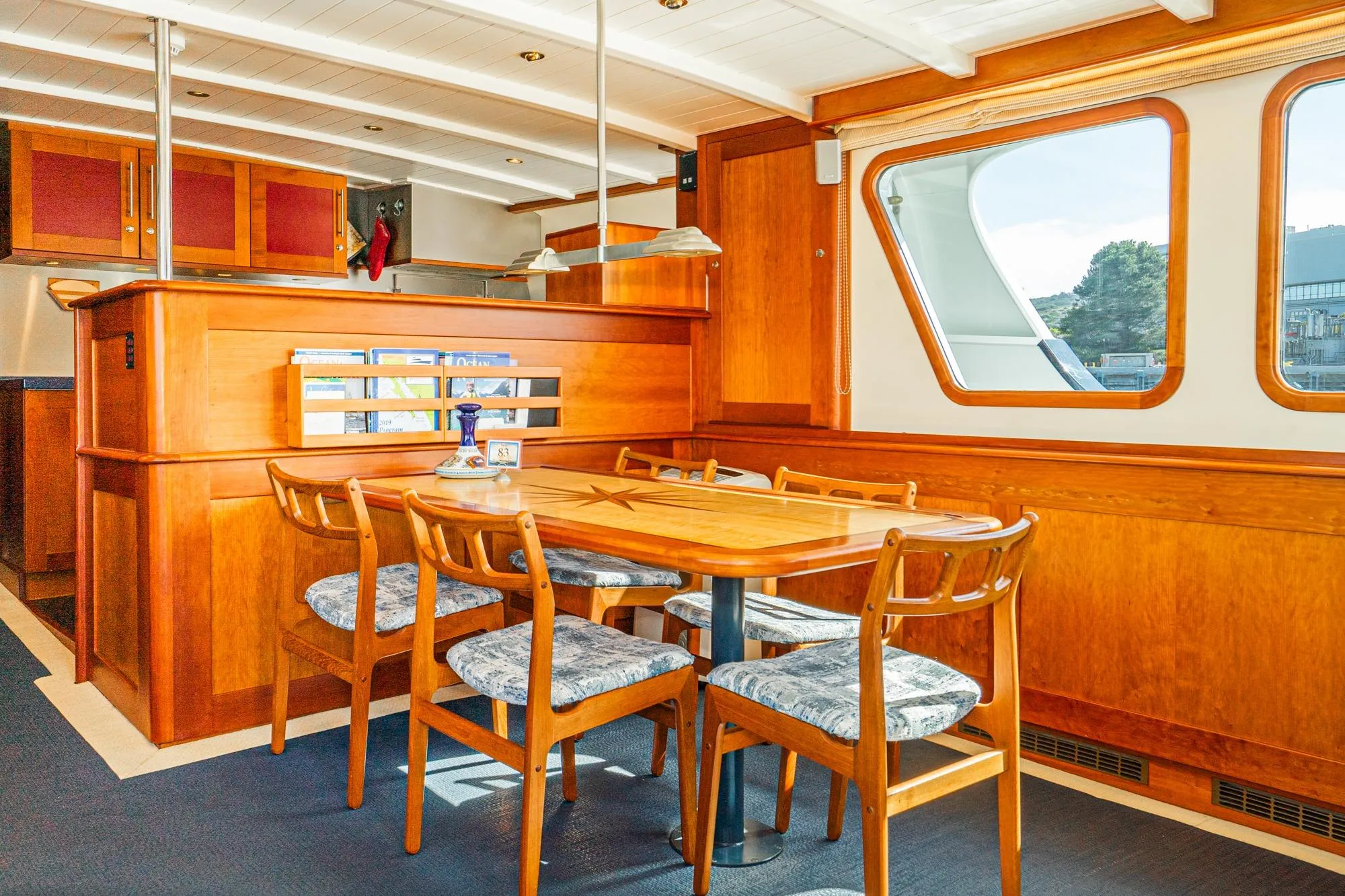 Interior of 1965 Van der Molen Custom yacht with wooden dining area and large windows.