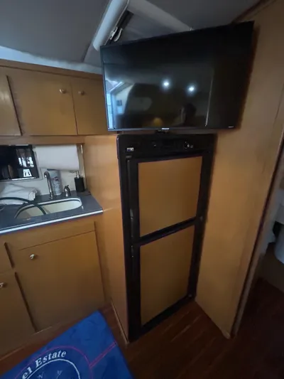 Reel Estate Yacht Photos Pics 1998 Tiara Yachts 3500 Express interior with kitchenette, fridge, and mounted TV.