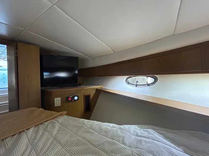 Reel Estate Yacht Photos Pics 1998 Tiara Yachts 3500 Express cabin interior with bed, TV, and porthole window.
