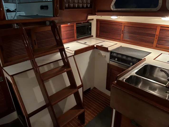 Helianthus Yacht Photos Pics 1985 Hinckley SW 42 yacht interior with wooden cabinetry and compact kitchen area.
