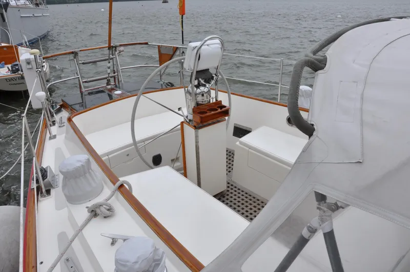 Helianthus Yacht Photos Pics 1985 Hinckley SW 42 sailboat cockpit with steering wheel and seating, docked on calm water.