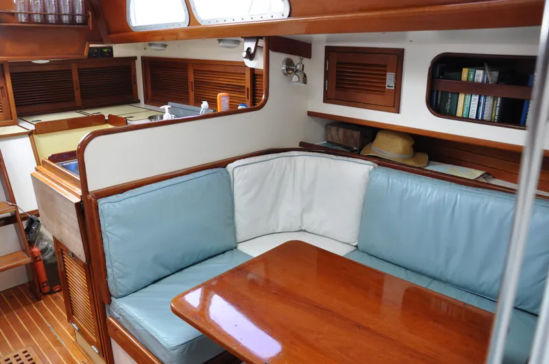 Helianthus Yacht Photos Pics Interior of 1985 Hinckley SW 42 sailboat with cushioned seating and wooden table.