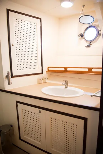 Zeewoelf Yacht Photos Pics Vintage 1963 Custom Mr. de Boot yacht bathroom with sink, porthole, and storage cabinets.