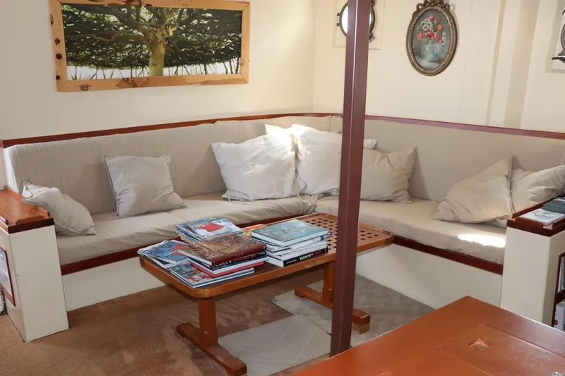 Zeewoelf Yacht Photos Pics Cozy boat interior with cushioned seating, wooden table, and decorative wall art, 1963 Custom model.