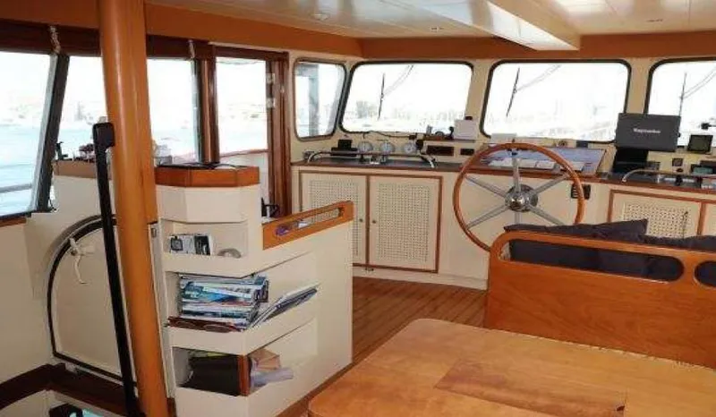 Zeewoelf Yacht Photos Pics Interior of a 1963 Custom Mr. de Boot boat, featuring a wooden steering wheel and navigation equipment.