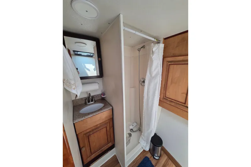  Yacht Photos Pics Compact bathroom in 2000 JM Custom 42, featuring shower, sink, and wooden cabinetry.