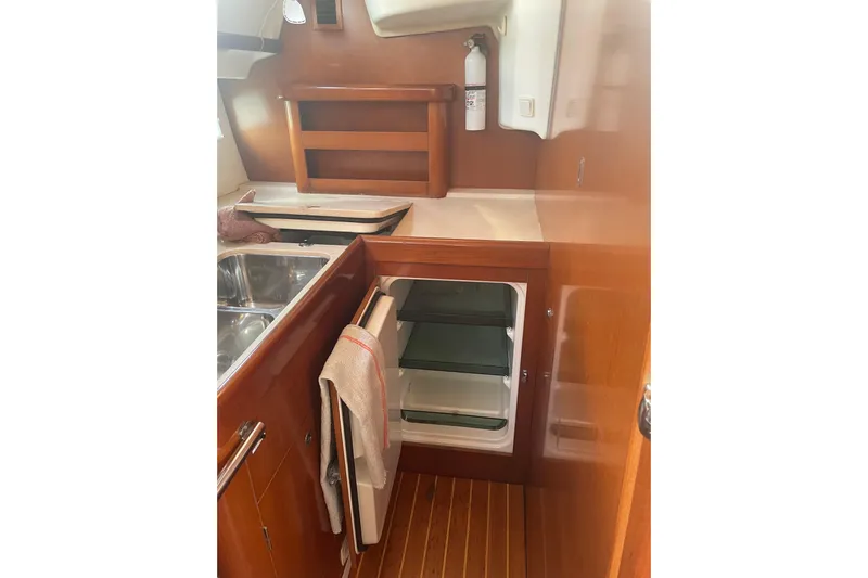 Kasoumai Yacht Photos Pics 2007 Beneteau 423 yacht kitchen with open fridge, wooden cabinetry, and stainless steel sink.