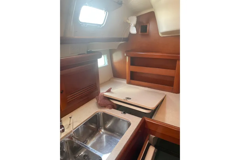 Kasoumai Yacht Photos Pics Interior of 2007 Beneteau 423 sailboat, featuring a compact kitchen with wooden cabinetry.