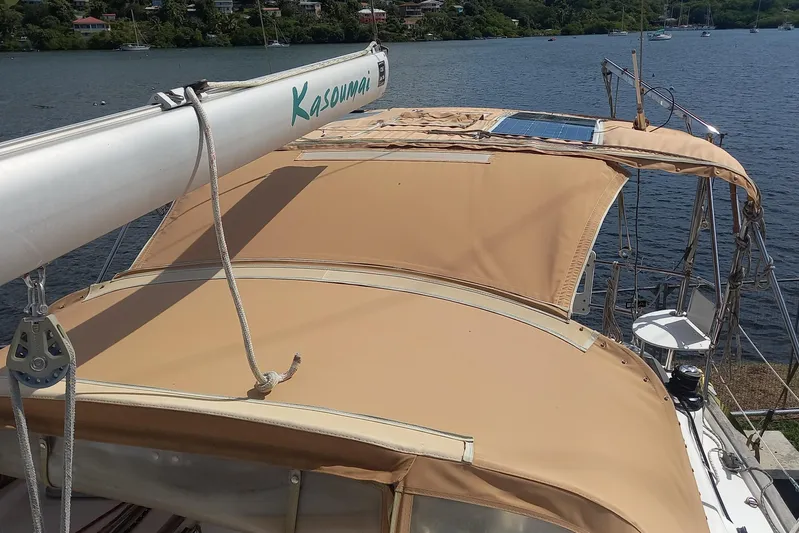 Kasoumai Yacht Photos Pics Sailboat Beneteau 423 (2007) with tan canopy docked by a scenic waterfront.