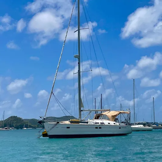 Kasoumai Yacht Photos Pics Sailboat Beneteau 423 (2007) anchored in a scenic harbor under a clear blue sky.