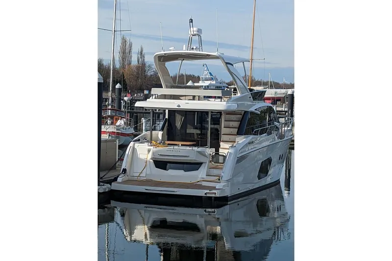 Ocean Love Yacht Photos Pics 2023 Absolute 50 Fly yacht docked in a marina, reflecting on calm water.