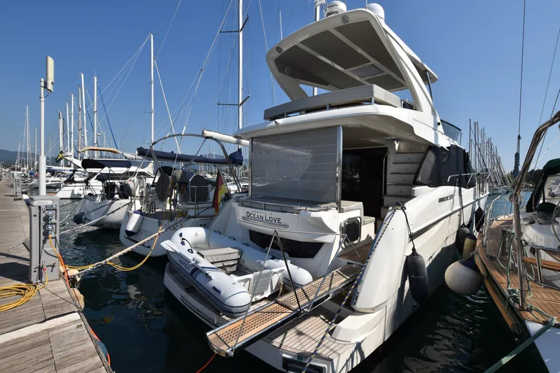 Ocean Love Yacht Photos Pics 2023 Absolute 50 Fly yacht docked at marina, surrounded by sailboats under clear blue sky.