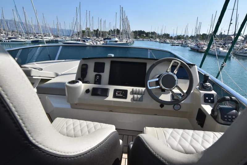 Ocean Love Yacht Photos Pics Cockpit view of 2023 Absolute 50 Fly yacht in marina, featuring modern steering and controls.