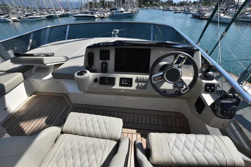 Ocean Love Yacht Photos Pics 2023 Absolute 50 Fly yacht helm with luxurious seating and modern controls in a marina.