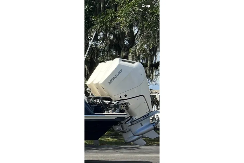  Yacht Photos Pics 2025 Scout 357 LXF boat with Mercury outboard engine, parked under trees.