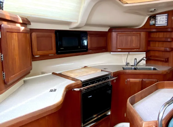 5th Row Center Yacht Photos Pics Hunter 430 yacht kitchen interior, 1997 model, featuring wooden cabinetry, stove, microwave, and sink.