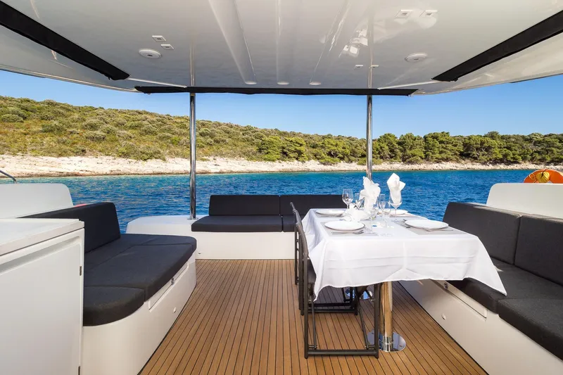 Catwalk Yacht Photos Pics Luxurious 2023 Lagoon 51 yacht interior with elegant dining setup, overlooking serene coastal waters.