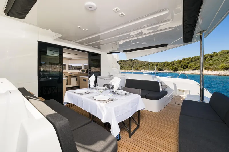Catwalk Yacht Photos Pics Luxurious 2023 Lagoon 51 yacht with elegant outdoor dining area and scenic ocean view.