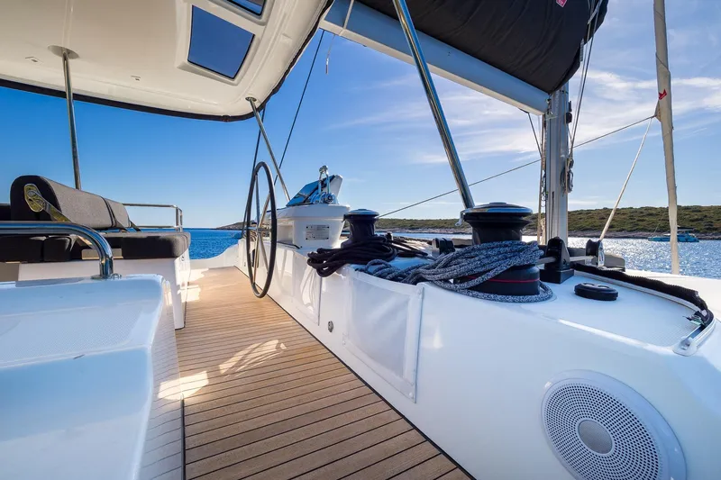 Catwalk Yacht Photos Pics 2023 Lagoon 51 yacht deck with steering wheel, ropes, and ocean view.