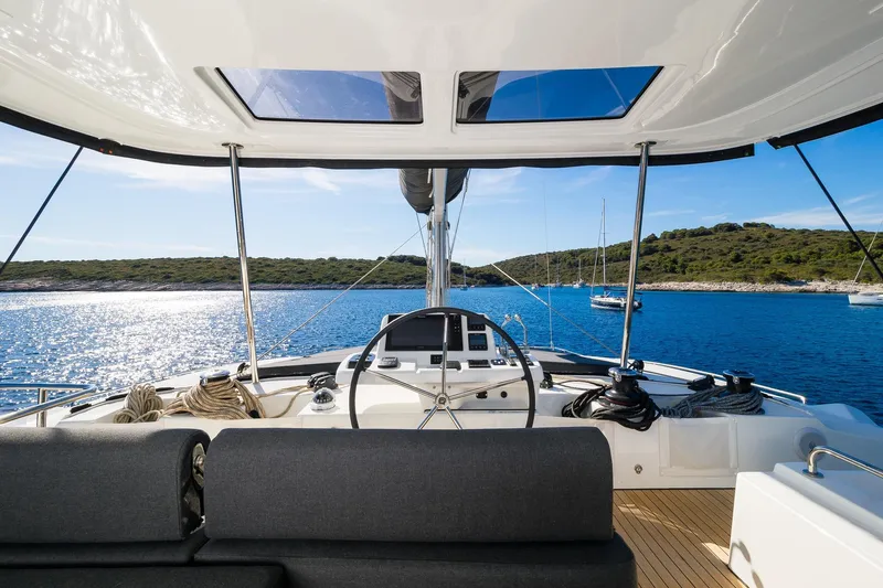 Catwalk Yacht Photos Pics Cockpit view of 2023 Lagoon LAGOON 51 yacht sailing in serene blue waters.