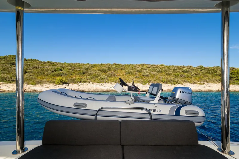 Catwalk Yacht Photos Pics Inflatable boat with Honda motor on Lagoon 51 yacht, 2023 model, near scenic coastline.